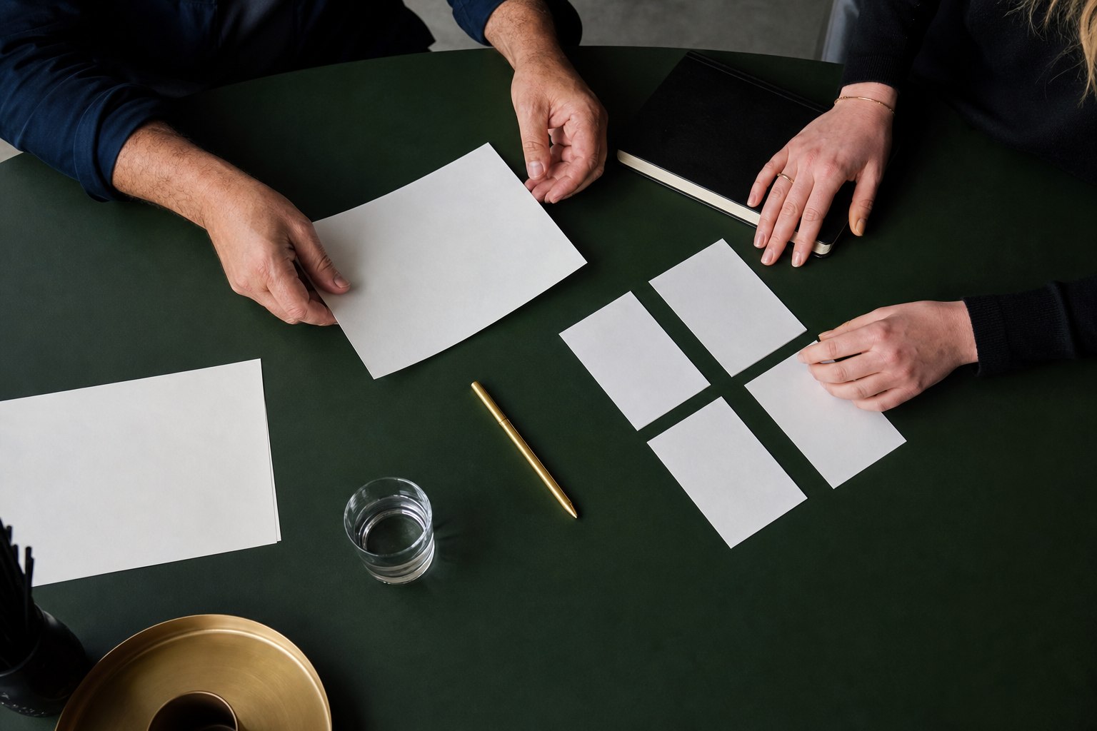 Drie mensen ordenen blanco kaarten en papier tijdens een campagnebriefing aan een donkergroene tafel